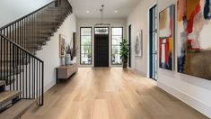 an entryway with stairs and paintings on the wall, along with wooden flooring