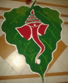 a painting on the floor with a red flower and green leaf in the shape of a woman's head