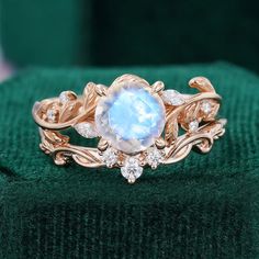 a gold ring with an oval blue stone surrounded by white diamonds on a green velvet surface