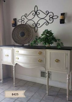 a white and black dresser sitting next to a potted plant on top of it