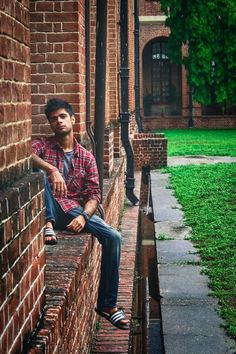 a man sitting on the side of a brick building