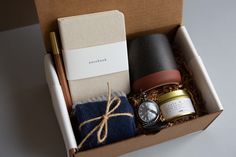 an open box containing two items including a watch, candle, and some other things