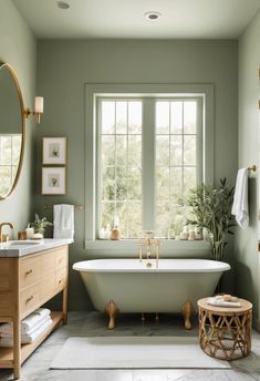 A large bathroom with sage green walls, a freestanding white tub, a light wood vanity with gold fixtures, and a marble countertop. Boho Sage Green Bathroom, Soft Green Bathroom Ideas, Green Trim Bathroom, Small Sage Green Bathroom, Sage Green House Decor, Sage Bathroom Ideas, Pink Green Bathroom, Bathroom Sage Green, Green And Gold Bathroom