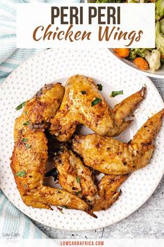 chicken wings on a white plate next to a bowl of broccoli and carrots