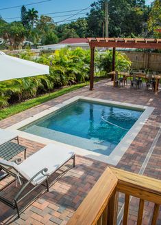 an empty swimming pool with lounge chairs and umbrellas on the patio area next to it