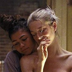 two women are embracing each other while one is holding her head to her chest and the other has her hand on her shoulder