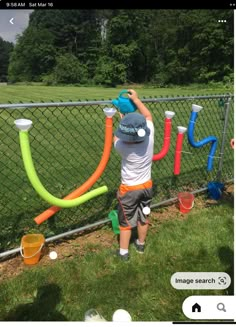 a man is painting the fence with plastic pipes