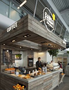 the inside of a coffee shop with lots of food on display and people walking around