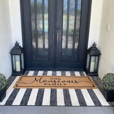 a front door with two lanterns and a welcome mat