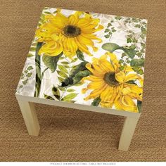 a table with sunflowers painted on the top and bottom, sitting on a carpeted floor