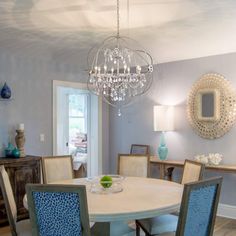 a dining room table with blue chairs and a chandelier hanging from the ceiling