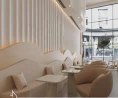 the interior of a modern restaurant with white walls and beige chairs, along with large windows