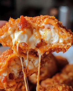 a close up of food being held by a person's hand with cheese and bacon on it