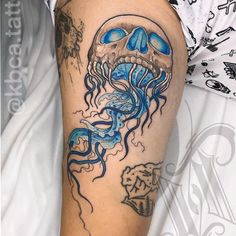 a man with a tattoo on his arm has a blue jellyfish in it's mouth