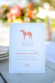 a card with a horse on it sitting on top of a table next to a plate