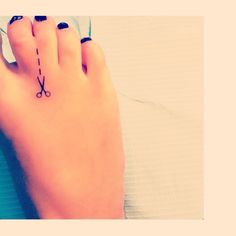 a woman's foot with a tattoo on it and scissors attached to the toe