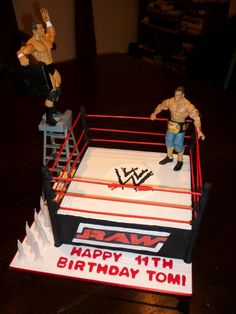 a birthday cake made to look like a wrestling ring with two wrestlers standing on it