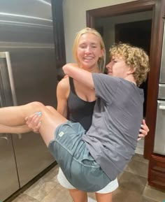 a man and woman are standing in front of a refrigerator with their arms around each other