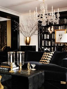 a living room filled with black furniture and a chandelier hanging from the ceiling