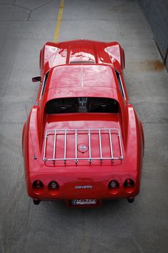 an old red sports car parked in a parking lot