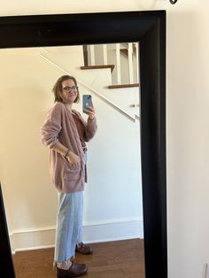 a woman standing in front of a mirror taking a selfie with her cell phone