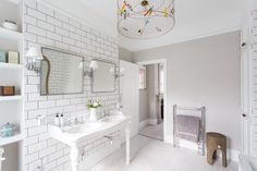 a white bathroom with two sinks and a chandelier hanging from the light fixture