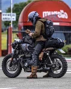 a man sitting on the back of a motorcycle while looking at his cell phone in front of a mcdonald's