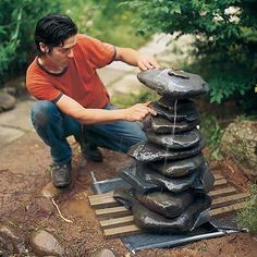 there is a man that is working on some kind of thing in the yard and it looks like he's making something out of rocks