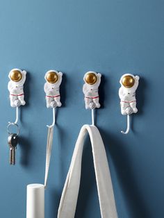 three white teddy bears are hanging on the wall with keys in each one's hooks