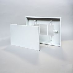 an empty white box with two doors open on a plain surface, showing the inside and outside