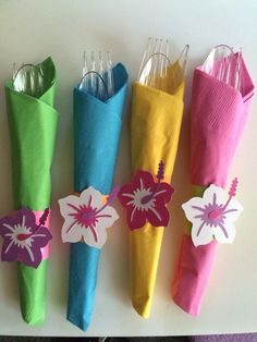 four colorful umbrellas are lined up on the wall with paper flowers attached to them