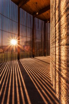 the sun is shining through some bars on a building's wall and casting long shadows