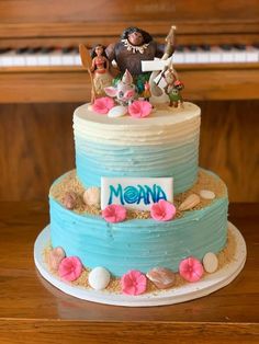 there is a blue cake with pink flowers on the bottom and an animal figurine on top