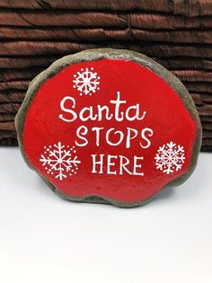 a red rock with the words santa stops here painted on it and snowflakes