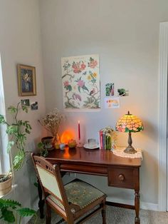 a wooden desk topped with a lamp next to a window