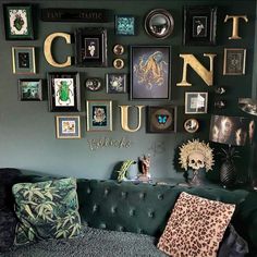 a living room filled with lots of framed pictures on the wall above a green couch