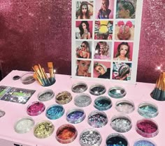 there is a pink table with many different colored powders and brushes in bowls on it