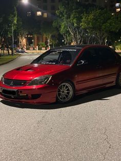 a red car is parked on the street at night