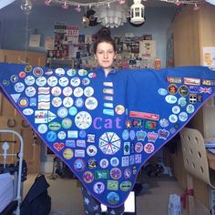 a woman holding up a large blue blanket with lots of stickers on it