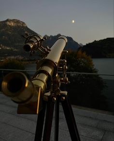 a telescope sitting on top of a wooden tripod next to a body of water