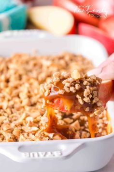 a hand holding a spoon full of baked oatmeal with apples in the background