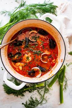 a large pot filled with seafood soup and garnished with parsley on the side