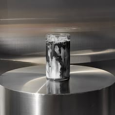 a glass sitting on top of a metal table next to a silver object with black and white designs