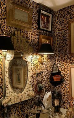 a bathroom with leopard print wallpaper and framed pictures on the wall, along with two lamps