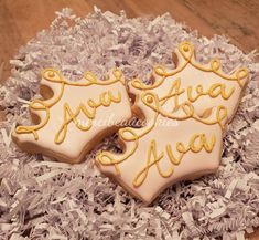 two decorated cookies sitting on top of shredded paper