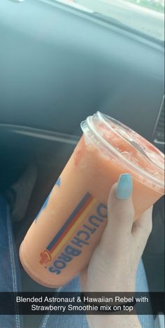 a person holding a drink in their hand while sitting in a car with the steering wheel behind them