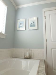 a white bath tub sitting under two framed pictures