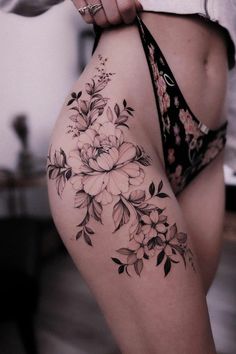 a woman's thigh with flowers on it and a black tie around her waist