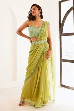 Green saree with pre-draped saree with pleated drapes, attached draped pallu and scalloped embroidered border. Paired with sweetheart neck padded blouse with all over pearl, sequin, badla, resham, cut dana embroidery and belt.
Components: 3
Pattern: Embellished
Type Of Work: Pearl, Sequin, Badla, Resham and Cut Dana Work
Neckline: Sweetheart Neck
Sleeve Type: Sleeveless
Fabric: Georgette, Opada Silk, Organza, Lining: Shantoon
Color: Green
Other Details: 
Scalloped cut work hem
Deep square back
A Saree Gowns, Draped Saree, Desi Outfits, Pleated Drapes, Padded Blouse, Drape Saree, Embroidered Border, Wedding Clothes, Green Saree