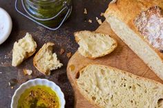 bread and butter sit on a cutting board next to a jar of pesto sauce